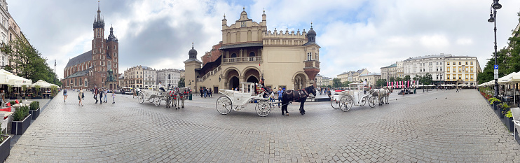 St Mary's Basilica and Cloth Hall in Rynek Główny medieval main square panorama, Krakow, Poland. Krakow city in Poland was originally the capital of the country until 1956 but is now best known for its well-preserved medieval centre with its period architecture, horse drawn carriages and spacious Rynek Glówny market square as well as the Jewish quarter and ghetto areas.