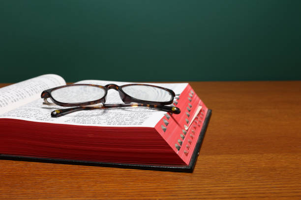 Close-Up Of Magnifying Glass On Open Book At Table