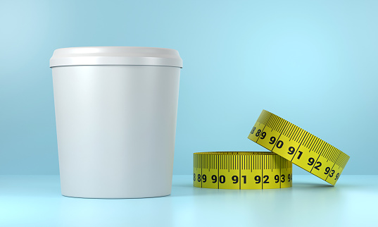 Empty yogurt box and tape measure on blue background. Healthy eating and diet concept.