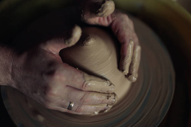 istock Hands of potter sculpt handmade earthenware bowl on spinning pottery wheel. 1421592820