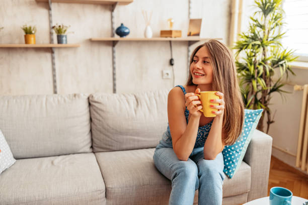 istock Young Woman Sitting On The Sofa And Drinking Coffee 1421597255