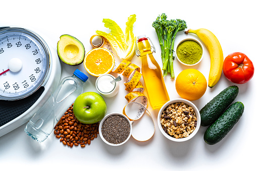 Overhead view of a composition of healthy food, weight scale and tape measure shot on white background. High resolution 42Mp studio digital capture taken with SONY A7rII and Zeiss Batis 40mm F2.0 CF lens