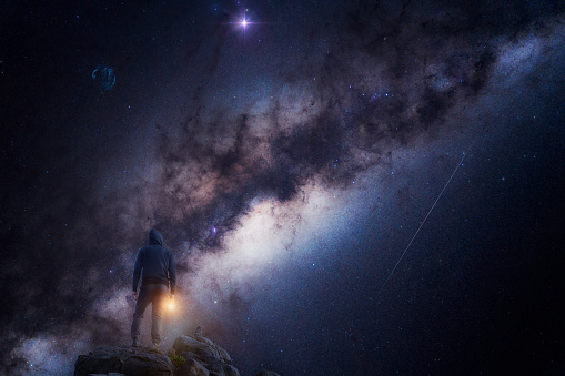 silhouette of a person from behind at night with the milky way and cosmos in the background