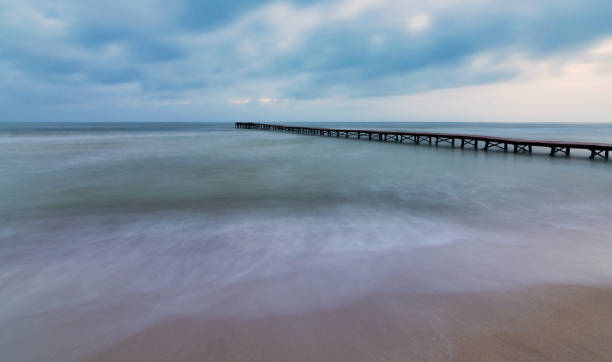 일몰에 조용한 해변에있는 나무 부두의 측면 전망. - boardwalk pontoon bridge landscape sky 뉴스 사진 이미지