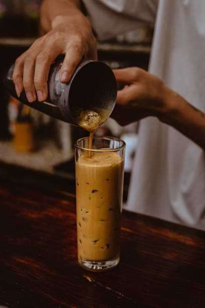 barista wlewanie milk shake coffee into highball drinking glass high resolution stock photo - milk shake coffee latté cold zdjęcia i obrazy z banku zdjęć