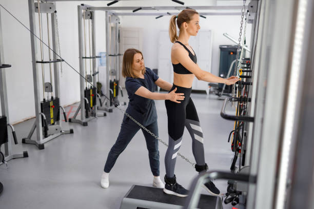 istock Woman doing exercise on decompression simulators with trainer rehabilitation. Sports physiotherapist assisting young female patient exercise therapy. Kinesitherapy technology 1421606730