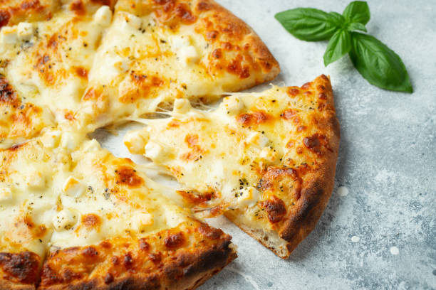 istock Italian pizza four cheeses with stretching cheese and basil on a light concrete background 1421607047