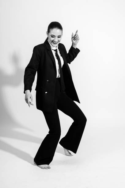istock Woman wearing classic black suit and dancing on studio white background 1421607151