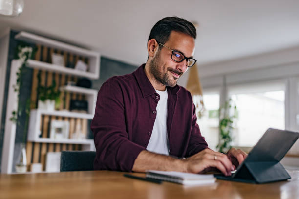 istock Adult man working over the tablet, typing something on the keyboard. 1421613405