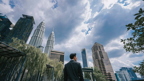 vista posteriore uomo d'affari asiatico cinese in piedi presso l'edificio per uffici del giardino pensile in città durante la mattina guardando lontano - roof men business city foto e immagini stock