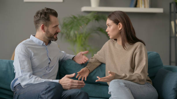 istock Serious Woman Talking to Man While Sitting on Sofa 1421618188
