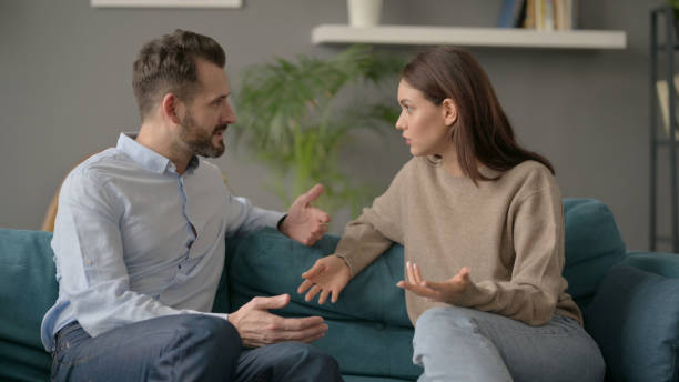 istock Woman Talking to Man While Sitting on Sofa 1421618521