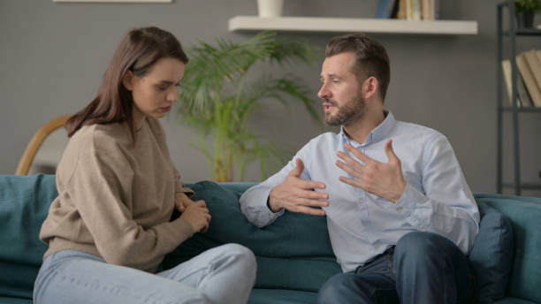istock Serious Man Talking to Woman While Sitting on Sofa 1421620022
