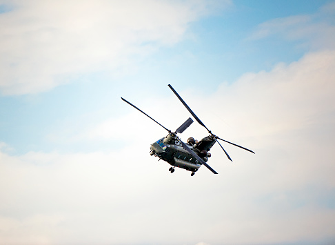 Boeing CH-47 Chinook Helicopter, Bournemouth, England. The Boeing CH-47 Chinook is a heavy-lift tandem rotor helicopter and among the heaviest lifting Western helicopters, seen here in flight over open sea with cumulus cloud formation in blue sky