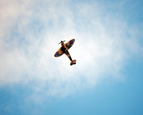 Supermarine Spitfire fighter, Bournemouth, England. Supermarine Spitfire single seat fighter from WW2 in flight over open sea with cumulus cloud formation in blue sky