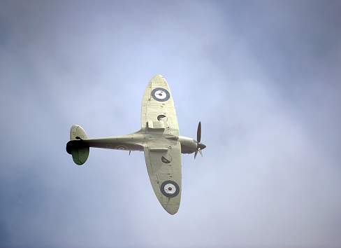 Supermarine Spitfire fighter, Bournemouth, England. Supermarine Spitfire single seat fighter from WW2 in flight over open sea with cumulus cloud formation in blue sky