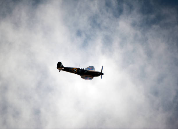 Supermarine Spitfire fighter, Bournemouth, England. Supermarine Spitfire single seat fighter from WW2 in flight over open sea with cumulus cloud formation in blue sky
