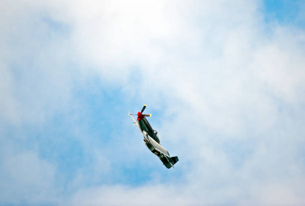 American P-51 Mustang fighter, Bournemouth, England. The North American Aviation P-51 Mustang was an American single seat, long-range, fighter and fighter-bomber used during conflicts such as World War II and the Korean War, seen here in flight over open sea with cumulus cloud formation in blue sky