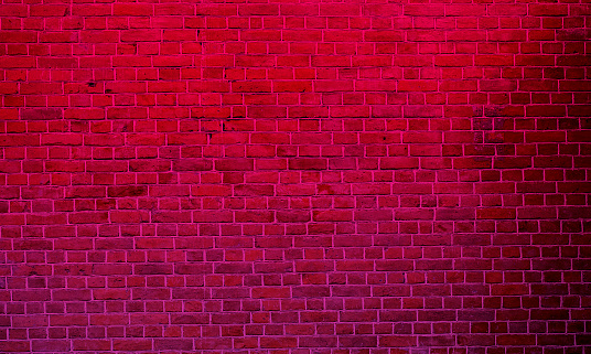 Red neon light over the long vintage brick wall