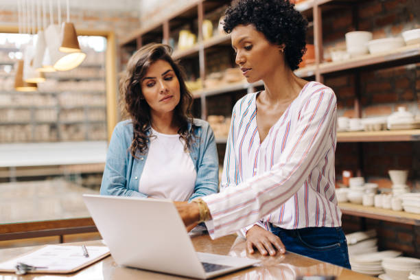 istock Two young businesswomen using a laptop together in their ceramic store 1421623196