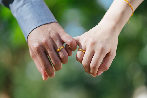 Close up of Asian couple holding hand with wedding band