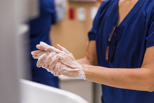 The unrecognizeable person uses soap to wash their hands in the hospital room.