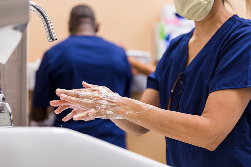 The medical personnel washes their hands in detail before assisting with a patient.