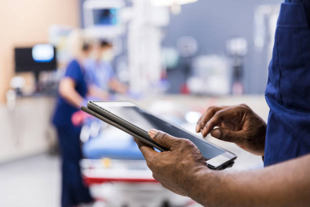 Unrecognizeable person using digital tablet The unrecognizeable medical staff uses digital tablet to review medical chart. stretcher stock pictures, royalty-free photos & images