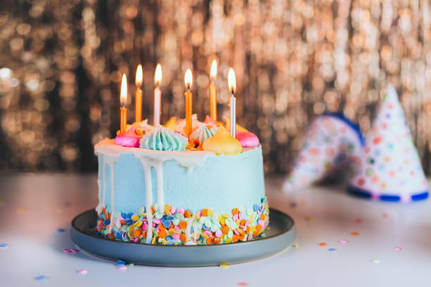 красочный праздничный торт с посыпками и горящими свечами и праздничными шапками на сверкающей золотой мишуре. праздничное празднование д - birthday cake cake birthday homemade стоковые фото и изображения