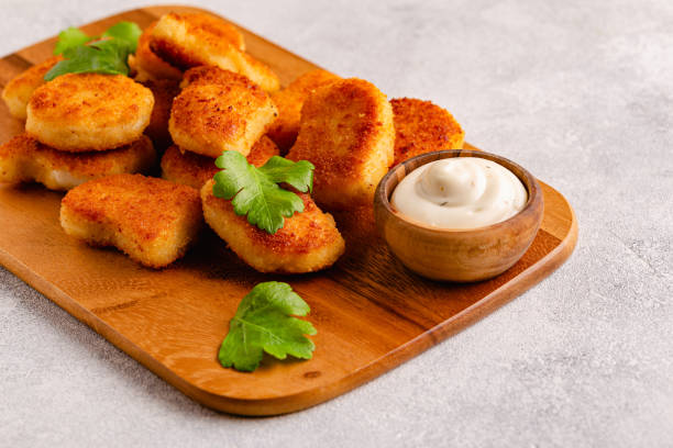 istock Fried crispy chicken nuggets on a wooden serving board. 1421631779