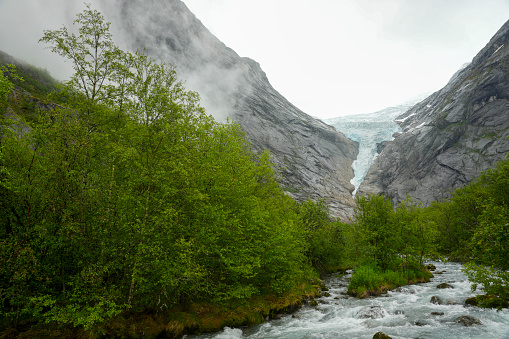 Waterfall and meltwater river in the valley approaching Briksdal Glacier in Norway.