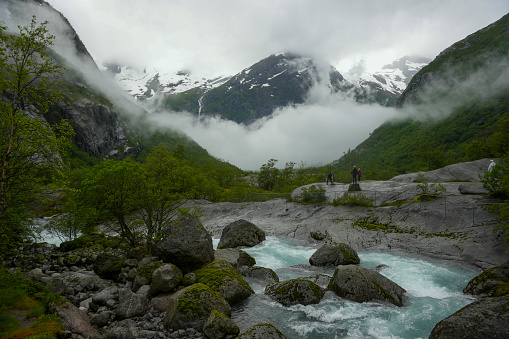 Waterfall and meltwater river in the valley approaching Briksdal Glacier in Norway.