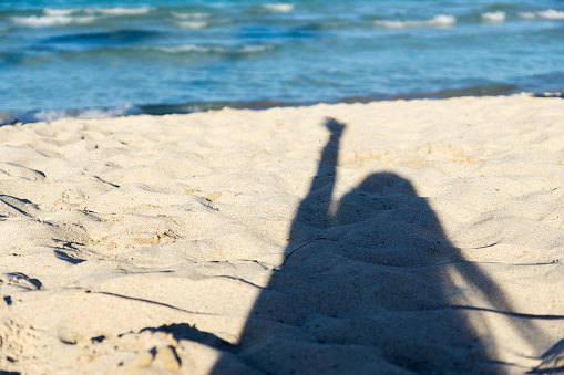 Hot summer day. Beautiful woman is lying on the beach under palm leaf