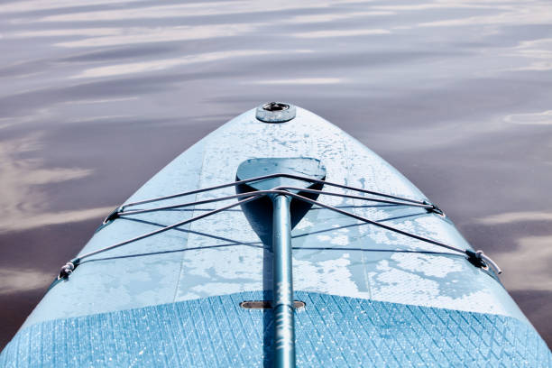 istock Drifting SUP board and surf board with paddle on sandy shore close up 1421636360