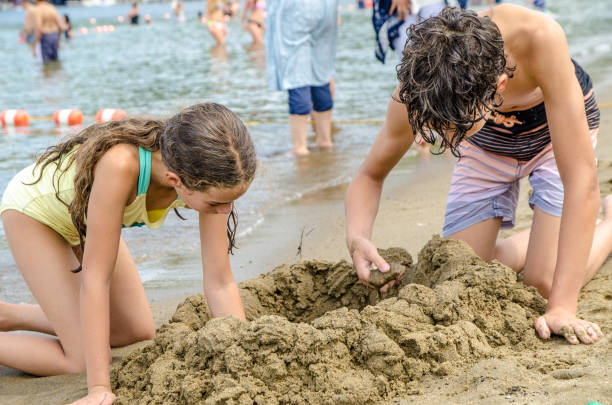 Kids playing on tropical beach. Water splash fun. Little boy splashing in sea waves. Children swim and play on summer family vacation. Sand and water toy, sun protection for young child.
