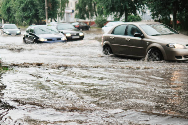 autos auf der straße überflutet von regen - sintflutartiger regen stock-fotos und bilder