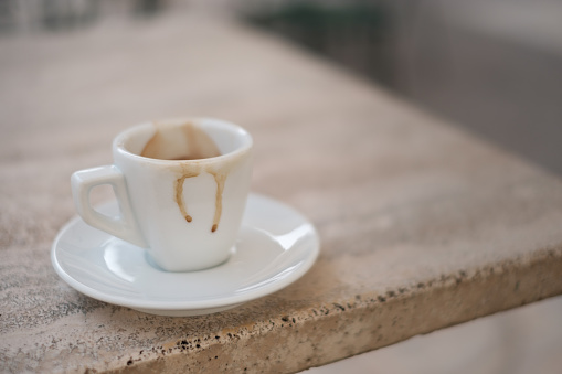 empty dirty espresso cup on marble table with bokeh for copy space