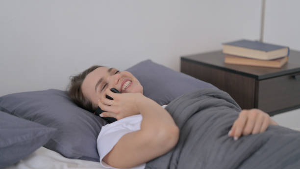 istock Woman Talking on Phone while Sleeping in Bed 1421648425