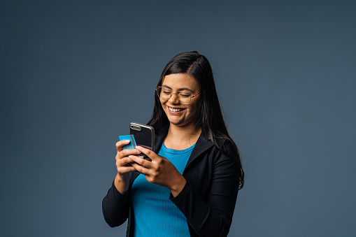 Portrait of a young woman holding a smartphone and credit card