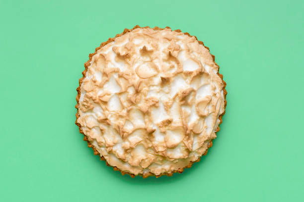 Top view with a homemade meringue pie isolated on a green background. Delicious lemon meringue cake minimalist on colorful table.
