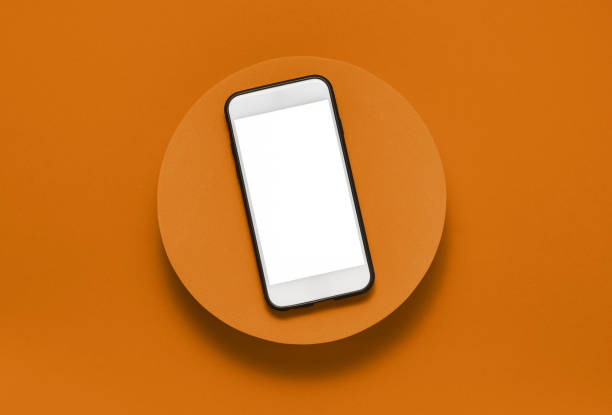 istock Blank screen mobile phone with clipping path on orange podium top view 1421650327