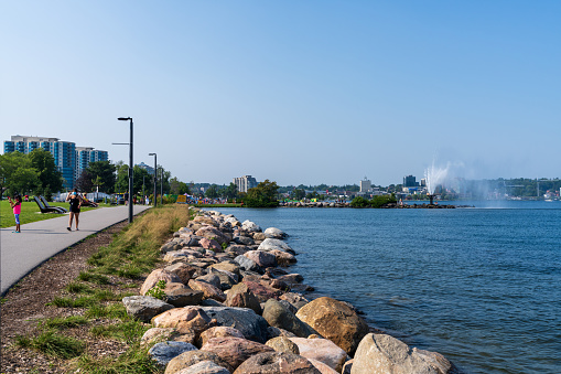Barrie, Ontario, Canada - July 25 2021 : Walking Path on shore of Kempenfelt Bay, Lake Simcoe in summer time. Centennial Park Waterfront Fountain.