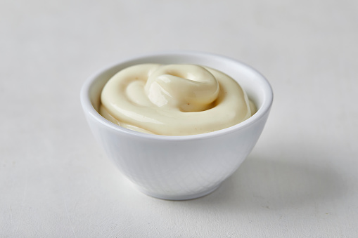 Mayonnaise swirl in a small ceramic bowl, on a kitchen table, close up macro