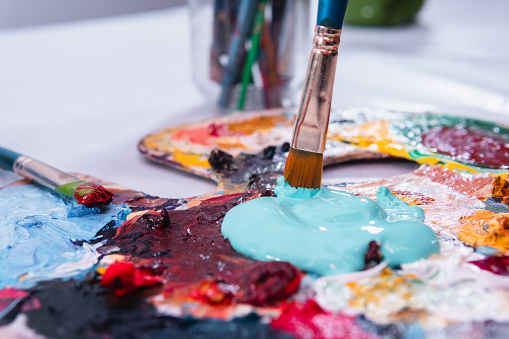 Close up of a color palette with a bunch of blue paint being mixed. Color palette with many stains from an artist's use.