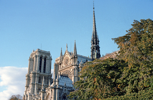 Paris, France - 1983: A vintage 1980's Fujifilm negative film scan of Notre Dame de Paris cathedral on a clear blue sky day.