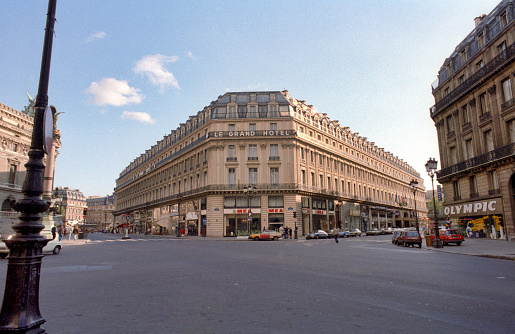 Paris, France - 1983: A vintage 1980's Fujifilm negative film scan of the city streets of Paris in front of the historic Le Grand Hotel.