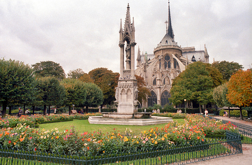 Paris, France - 1983: A vintage 1980's Fujifilm negative film scan of Notre Dame de Paris cathedral rear gardens on a cloudly overcast day.