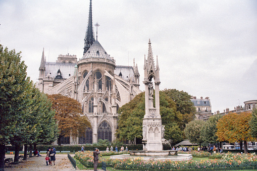 Paris, France - 1983: A vintage 1980's Fujifilm negative film scan of Notre Dame de Paris cathedral rear gardens on a cloudly overcast day.