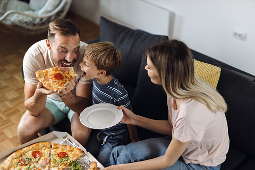 Happy father and son enjoying while eating pizza  at home