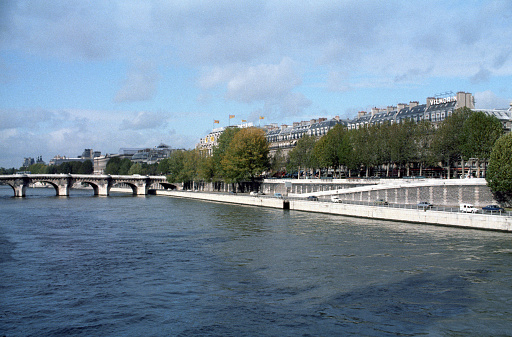 Paris, France - 1983: A vintage 1980's Fujifilm negative film scan of a bridge across the Seine river in Paris, France on a bright blue sky day.